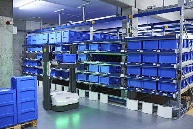 AMR operating beside warehouse racking, highlighting autonomous navigation in tight aisles to improve storage density, reduce travel time, and increase flexibility in fulfillment operations.