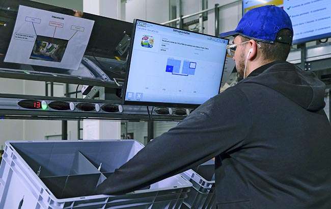 Worker at a Pick-it-Easy workstation reviewing information on a monitor, demonstrating ergonomic design, guided processes, and efficient KNAPP-supported picking for high‑accuracy fulfillment.