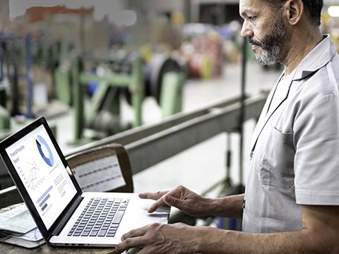 Man working on a laptop analyzing demand forecasts to prevent costly over‑planning or under‑planning and ensure accurate, efficient labor and resource allocation.