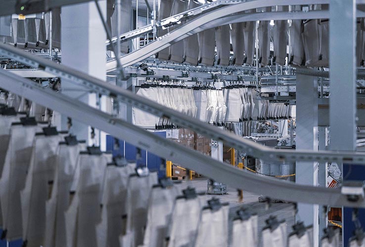 High-capacity pocket conveyors from KNAPP transporting hanging and flat goods with smooth, continuous flow to improve order sequencing, buffering, and omnichannel fulfillment efficiency.