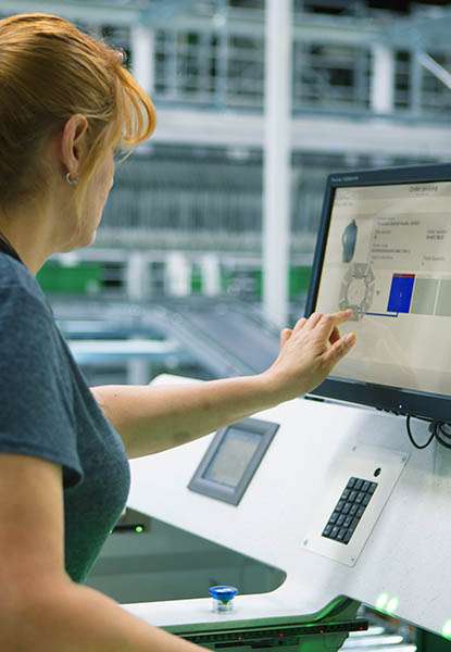 retail worker operating a modern fulfillment workstation with organized goods digital displays and pick to light technology illustrating efficient order processing and the role of ergonomic workstations in supporting fast accurate retail fulfillment.