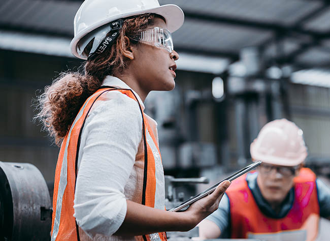 female warehouse worker in a safety jacket operating in a modern distribution center to manage tasks efficiently.