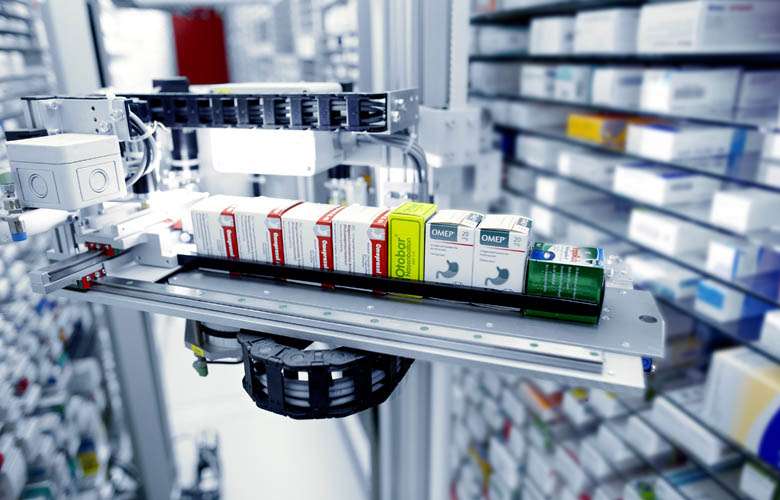 KNAPP pharmacy‑automation technology displayed in a distribution‑center environment, illustrating software that streamlines labor management, integrates transportation and shipment tracking to the store, and provides CMMS‑driven real‑time insights for proactive and predictive maintenance.