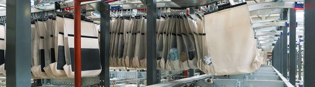 large scale pocket conveyor system moving individual pouches along overhead tracks in a high volume distribution center demonstrating efficient item buffering sequencing and sortation for fast accurate omnichannel fulfillment.
